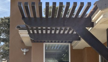 An awning attached to a home with the sun shining on it.